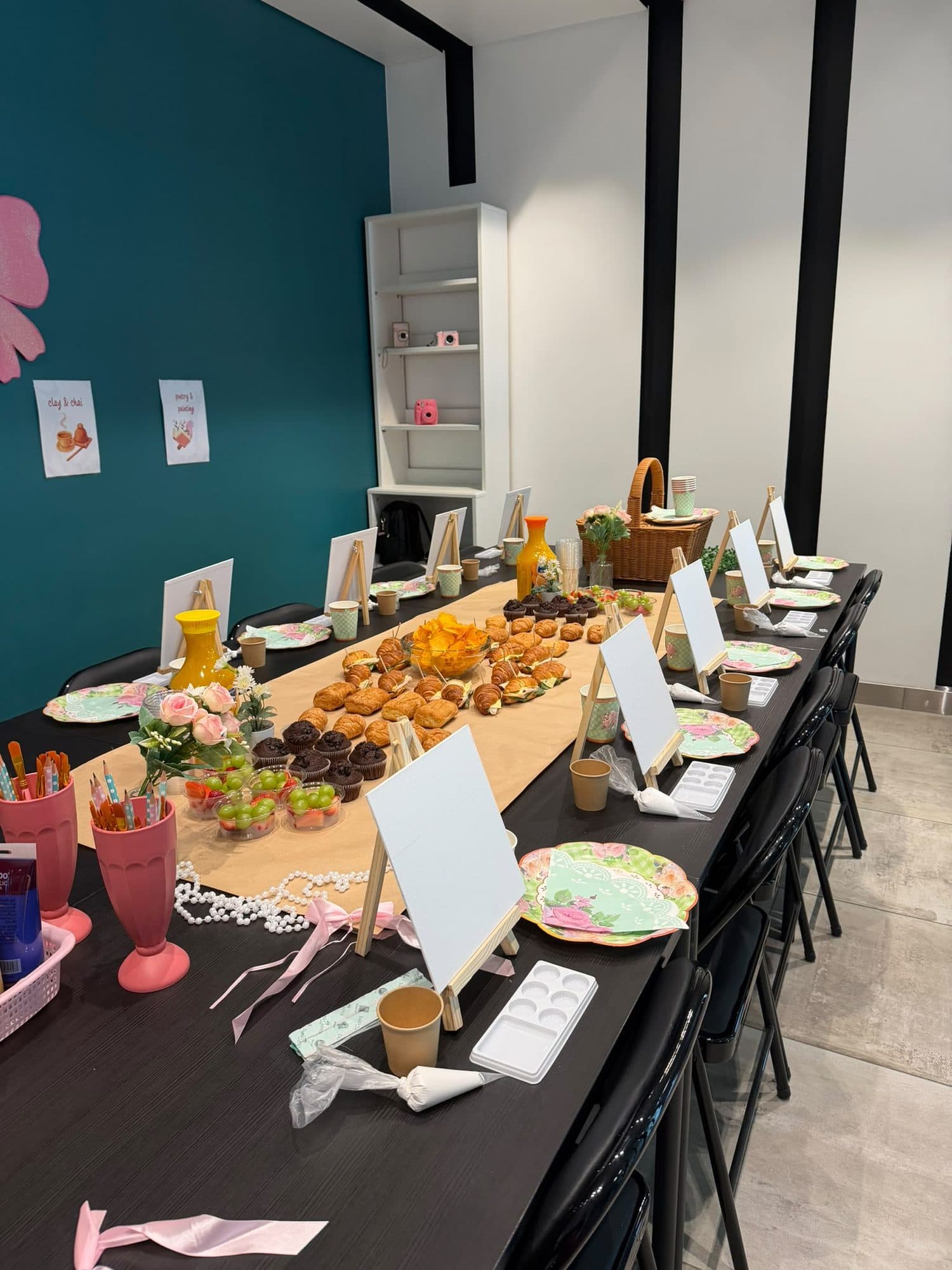 Long workshop table set with easels, canvases, flowers and pastries